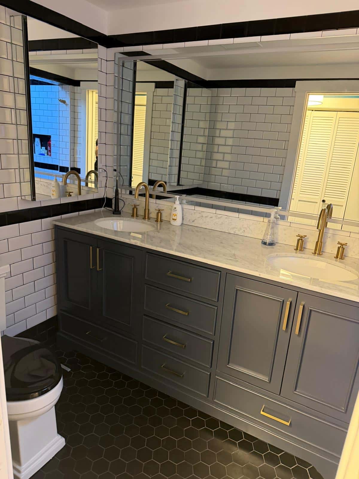 Double vanity with marble top, brass fixtures and white subway tile after cleaning