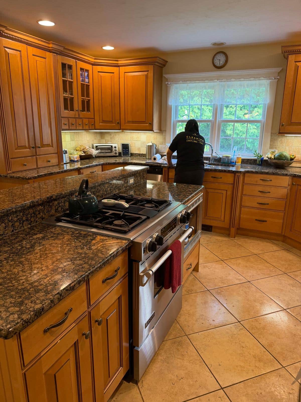 Global Facility Service team member in uniform cleaning a kitchen with a granite island