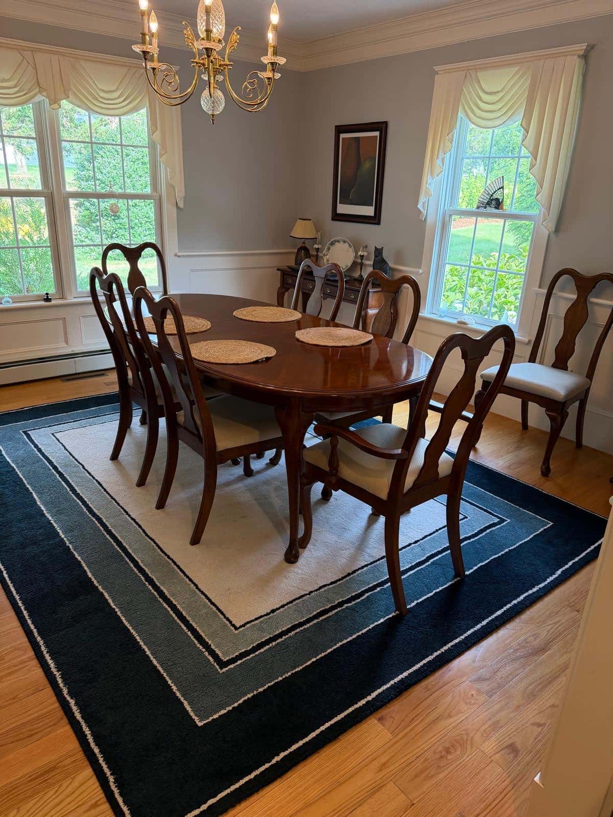 Formal dining room with a cherry table, brass chandelier and area rug after cleaning